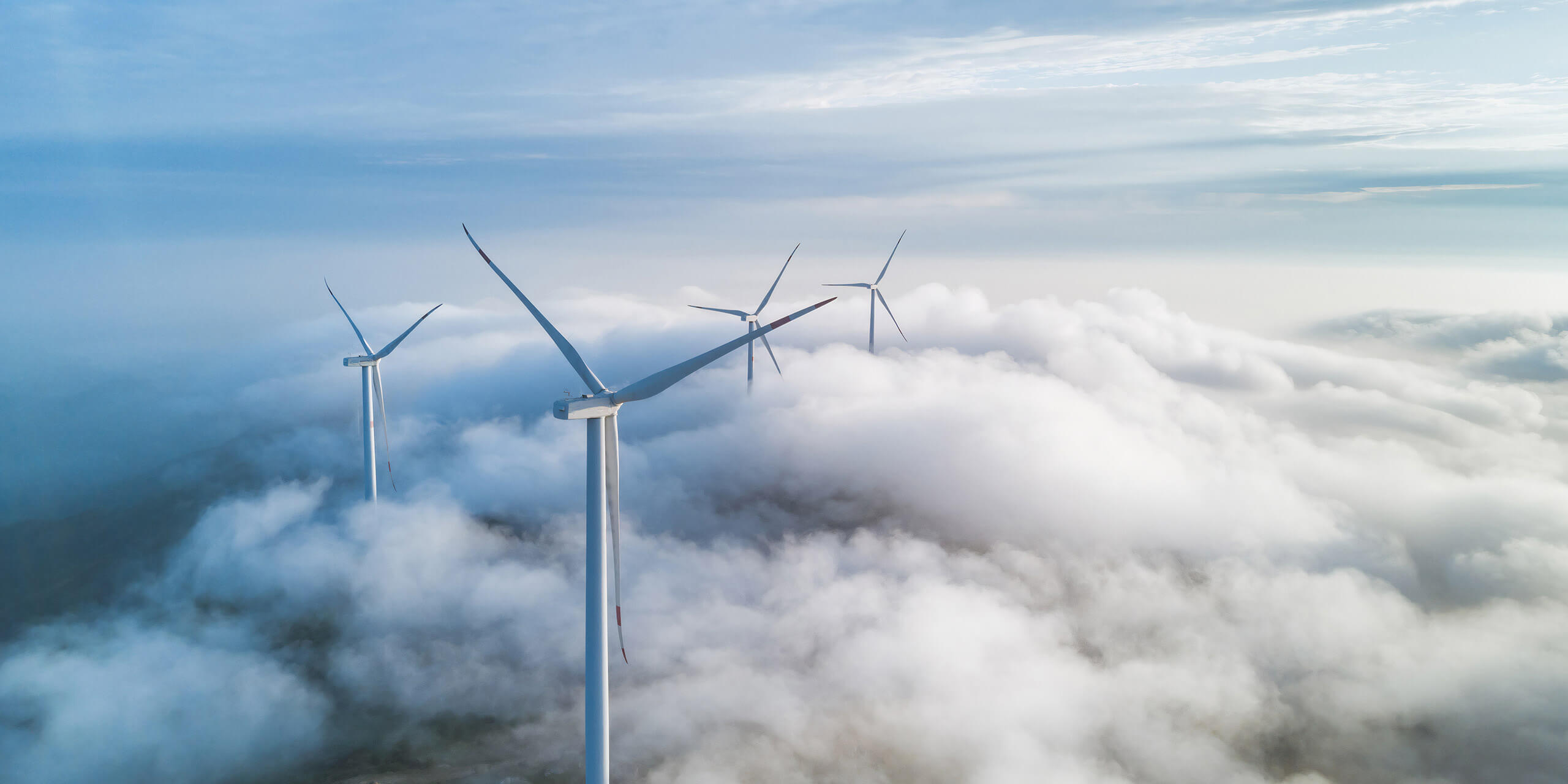 four windturbines standing between clouds